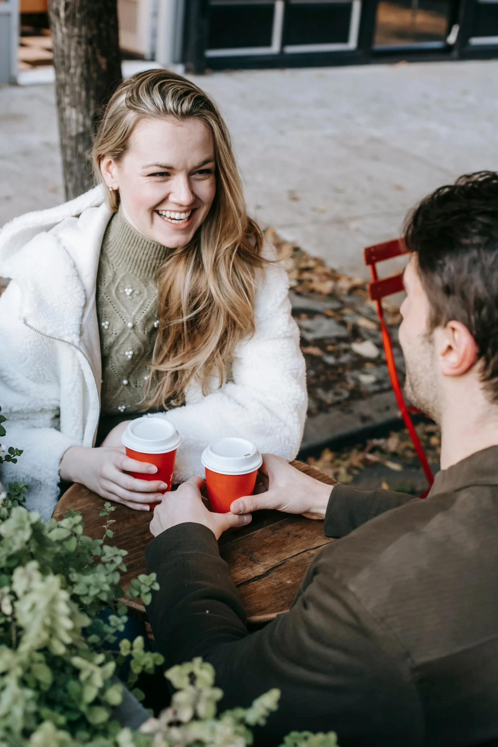 Two people sharing a cheerful conversation over coffee at an outdoor cafe
