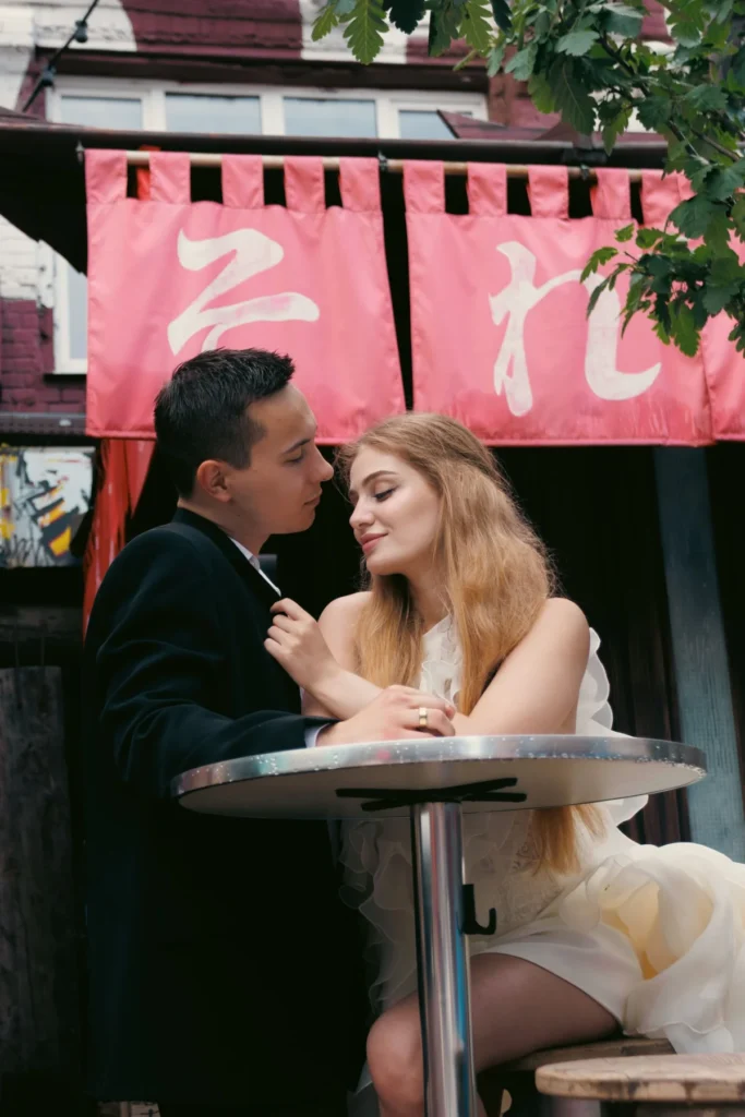 A romantic couple shares an intimate moment at an outdoor cafe, surrounded by charming decor.