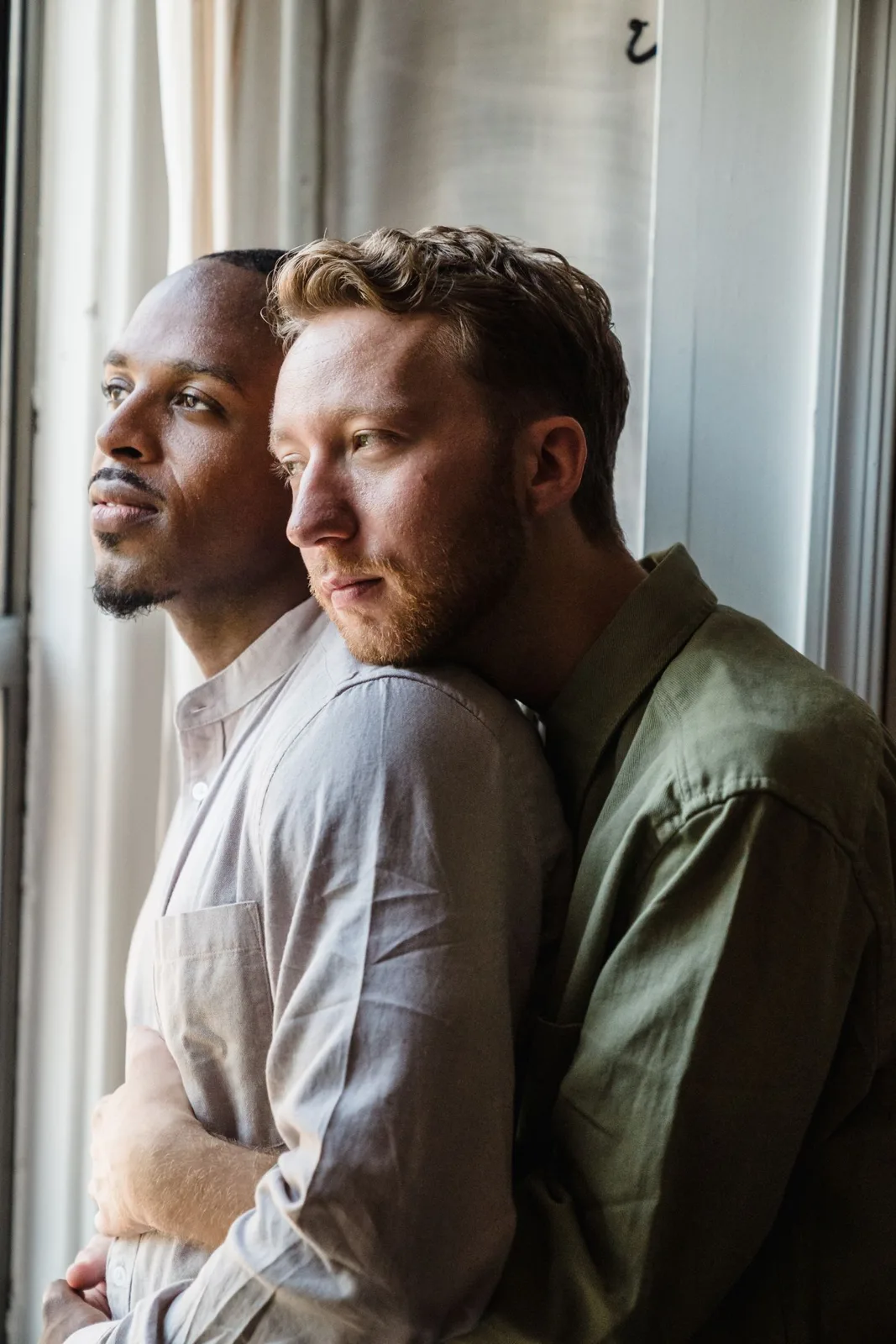 A loving couple embraces by the window, capturing a tender moment of connection.