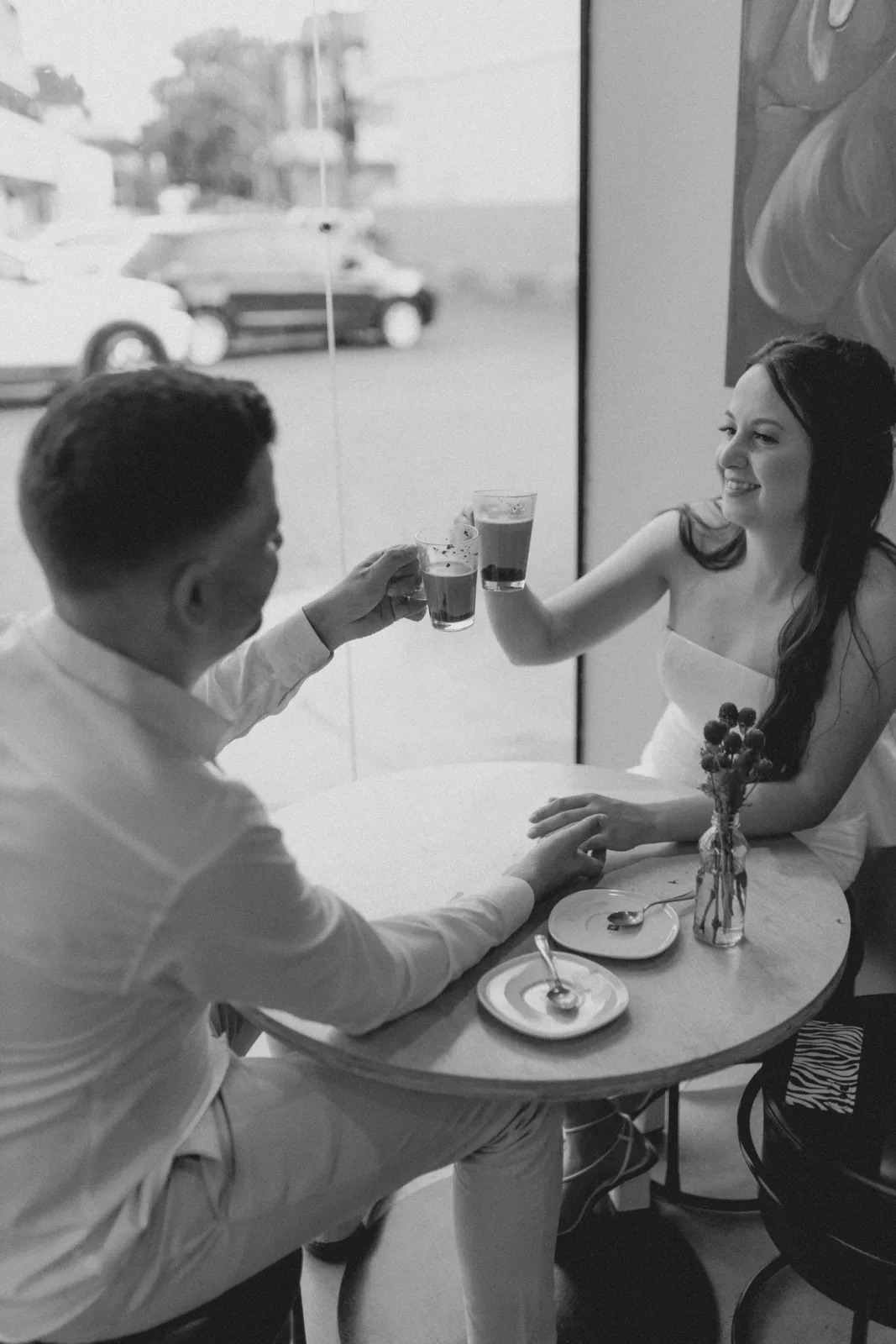 A couple enjoys coffee and companionship in a modern café, holding hands and smiling.