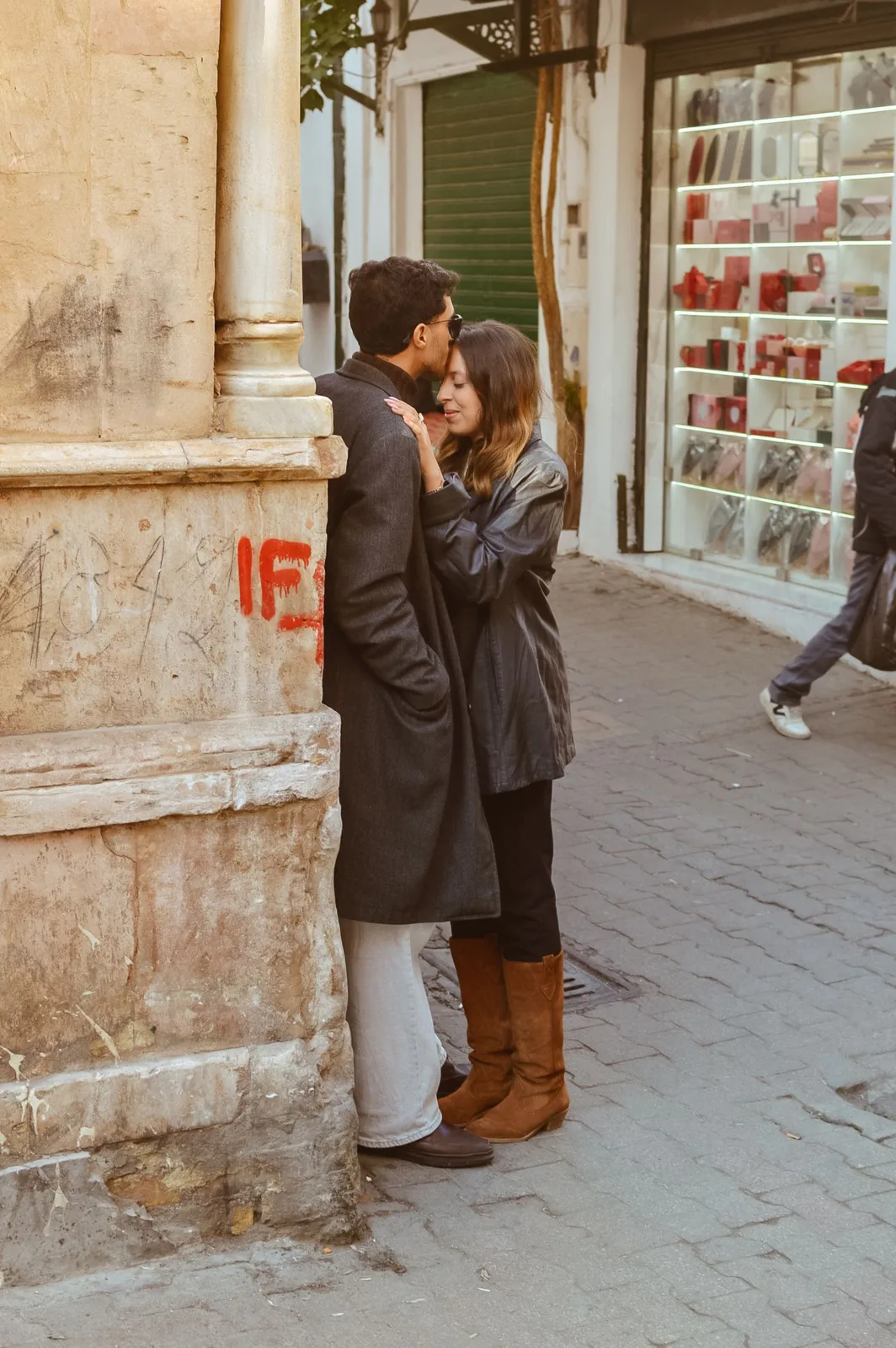 A couple in a warm embrace on a city street corner, capturing a tender urban moment.