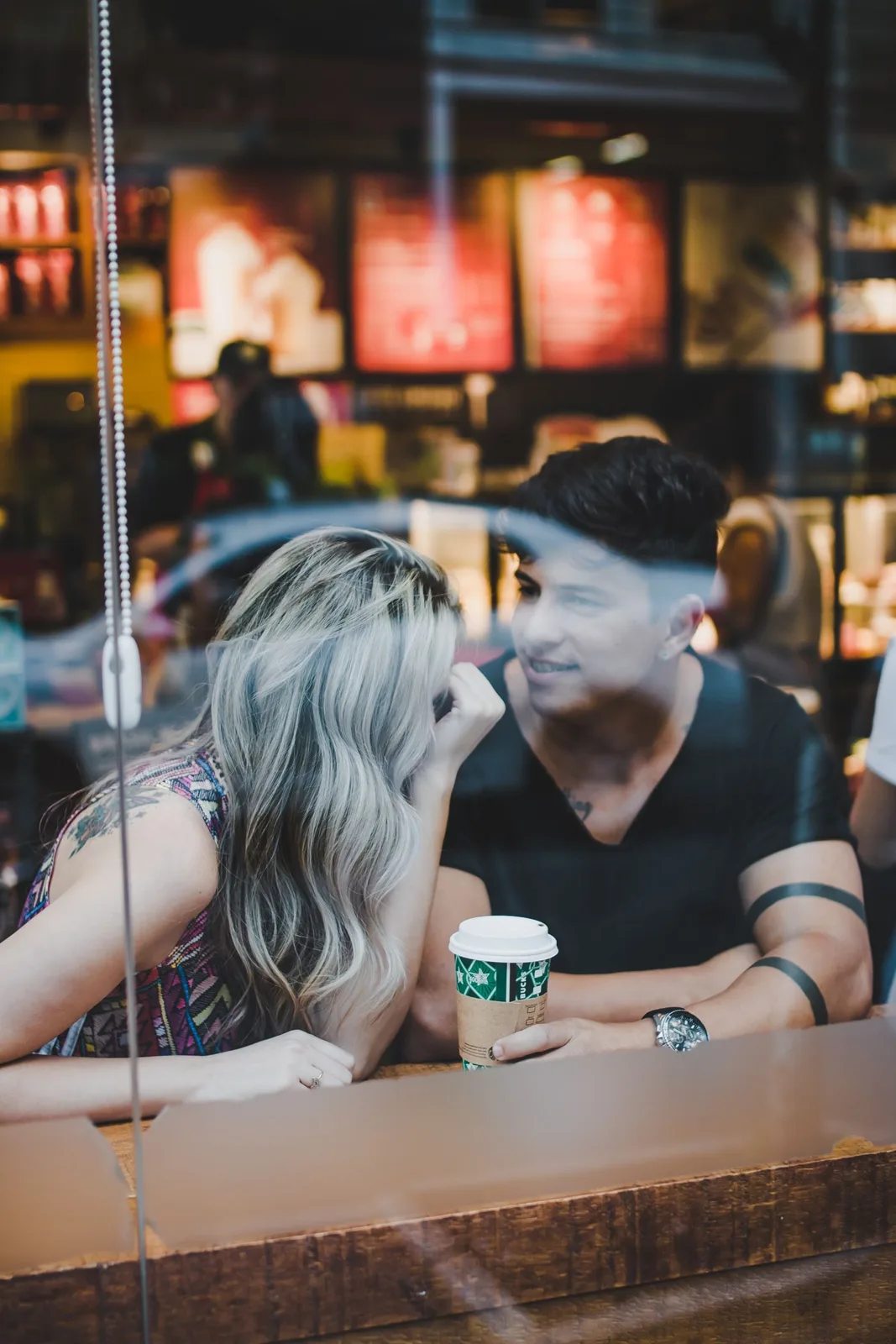 A couple enjoying a coffee date inside a modern café with smiles and conversation.