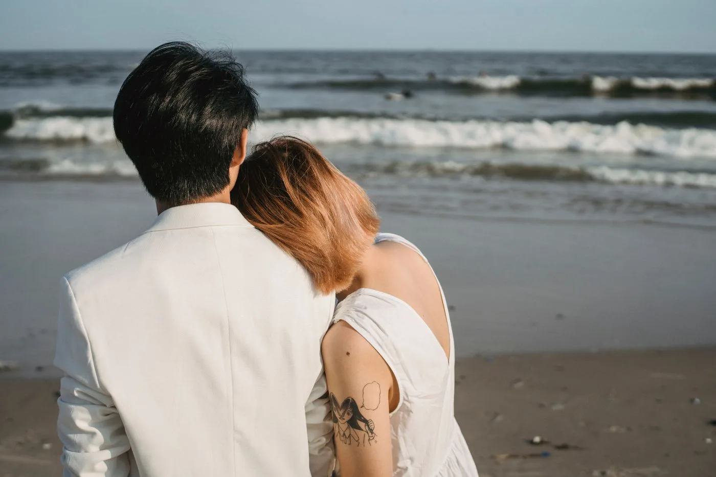 A romantic moment with a couple embracing on a sandy beach, waves crashing nearby.