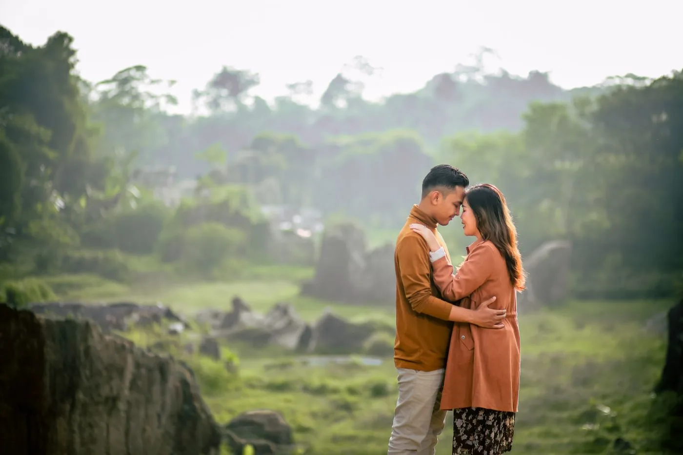 A loving couple shares a romantic moment in a green, serene park during summer.