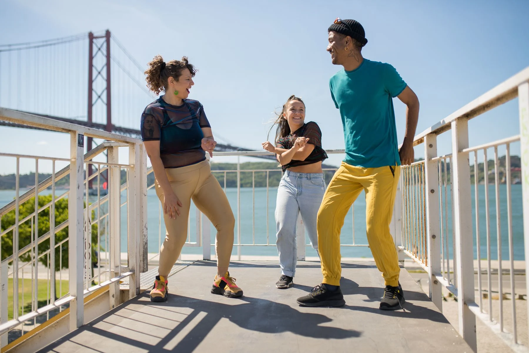 Three adults dancing together beside the water