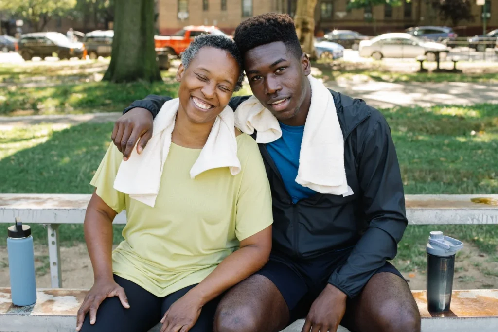 A smiling couple relaxes on a park bench after exercising, embodying health and companionship.