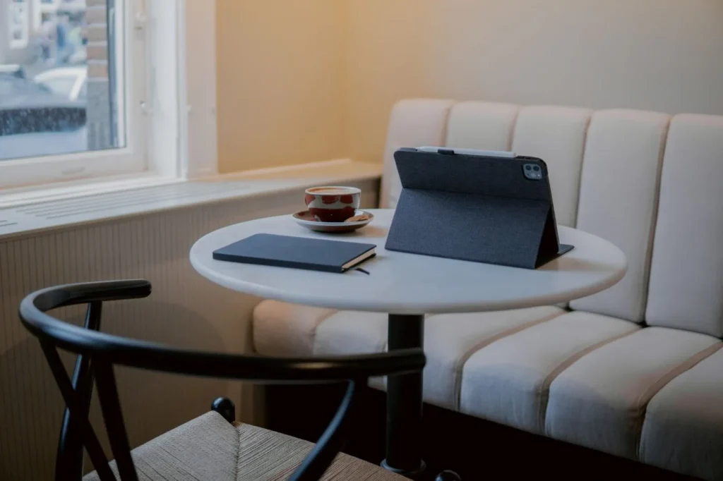 Serene cafe nook in Amsterdam featuring a tablet, notebook, and coffee cup on a white marble table.