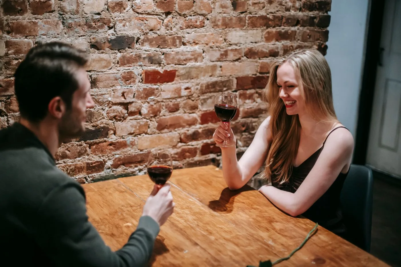 A couple enjoys a romantic dinner date with wine, exchanging smiles and affection.