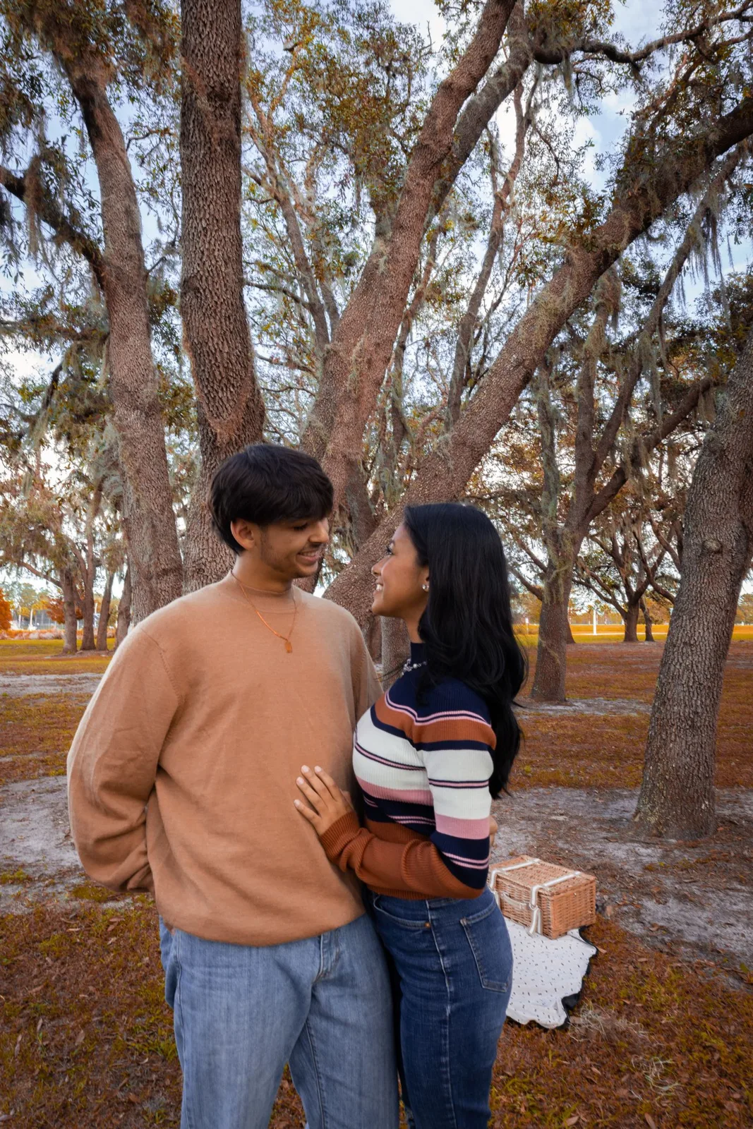 Happy couple embracing during a fall picnic in a scenic park setting.
