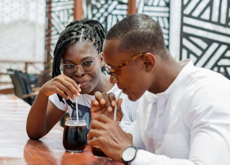 Young couple sharing a drink at an outdoor café in Accra, showcasing love and companionship.