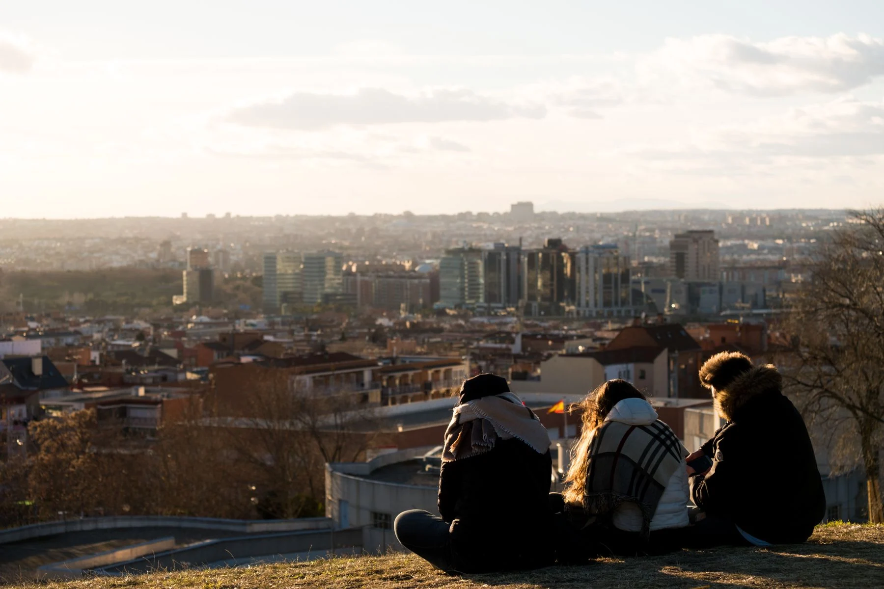 Three adults sitting together overlooking a city at sunset