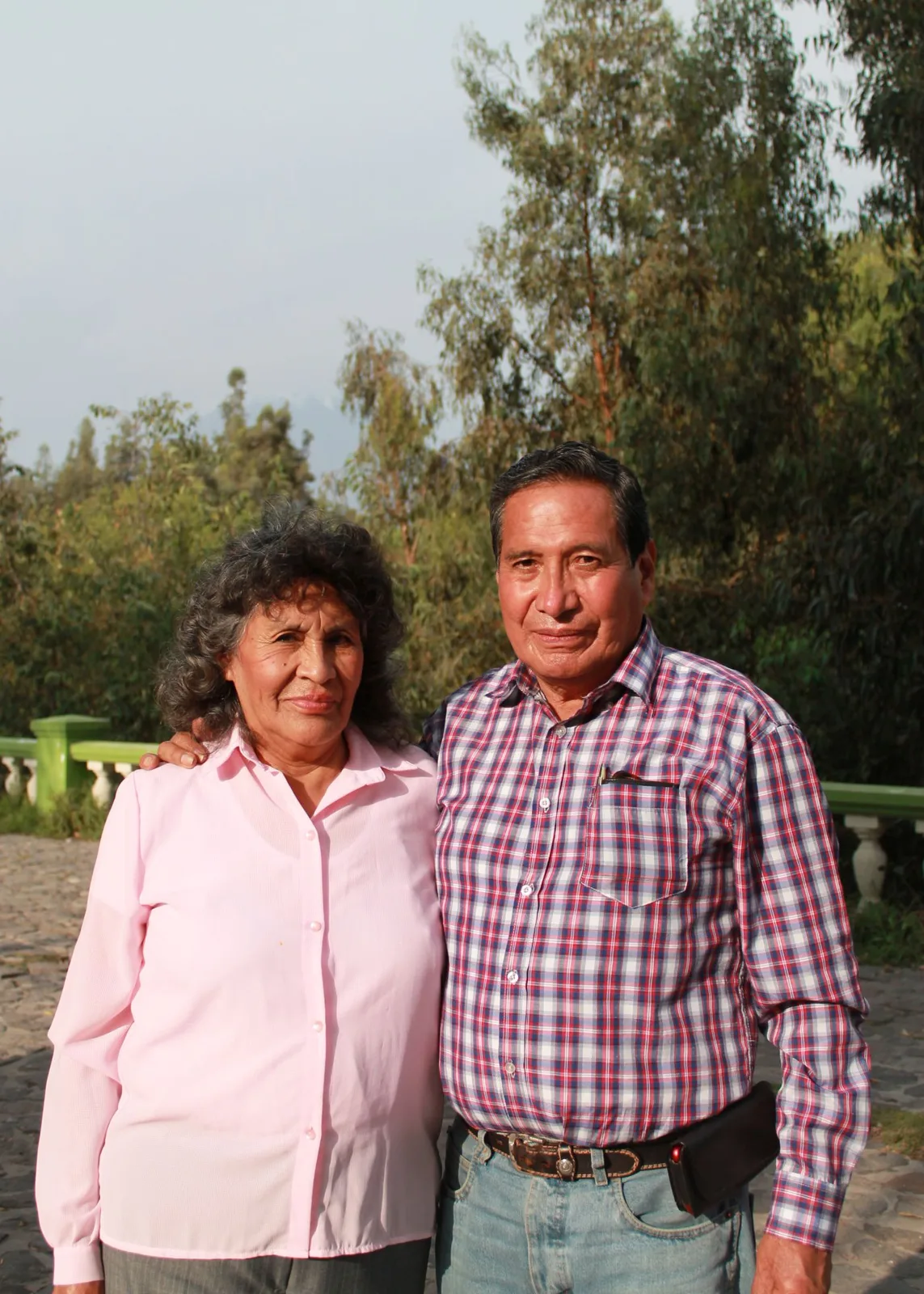 Senior couple smiling outdoors against a natural backdrop, conveying love and companionship.