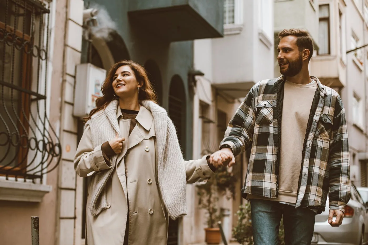 Happy couple holding hands while walking together down a picturesque city street.