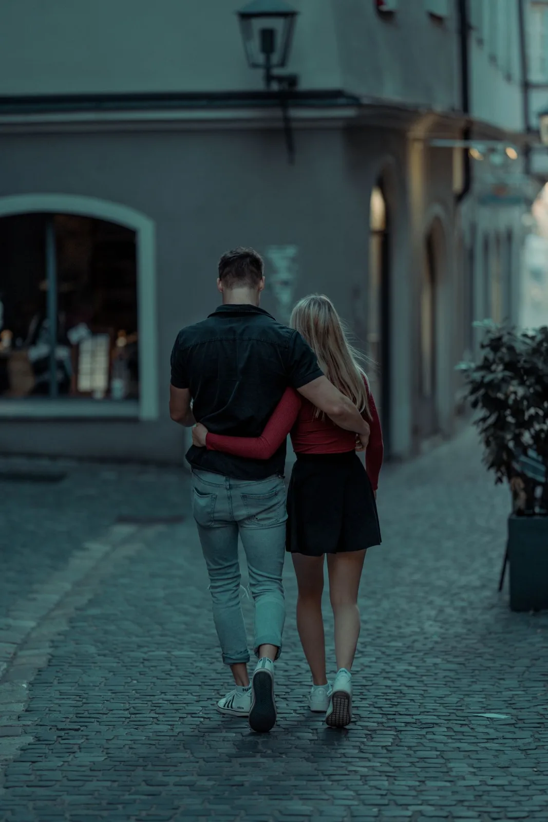 A young couple enjoying a romantic walk on a cobblestone street during daytime.