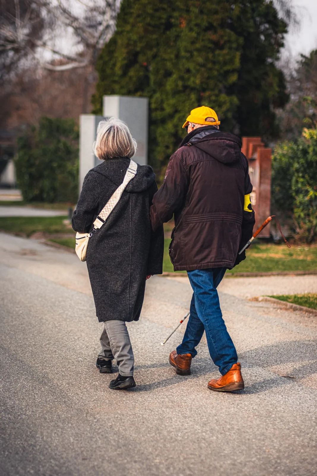 Two senior adults walking on a street during winter, dressed warmly and enjoying outdoor companionship.