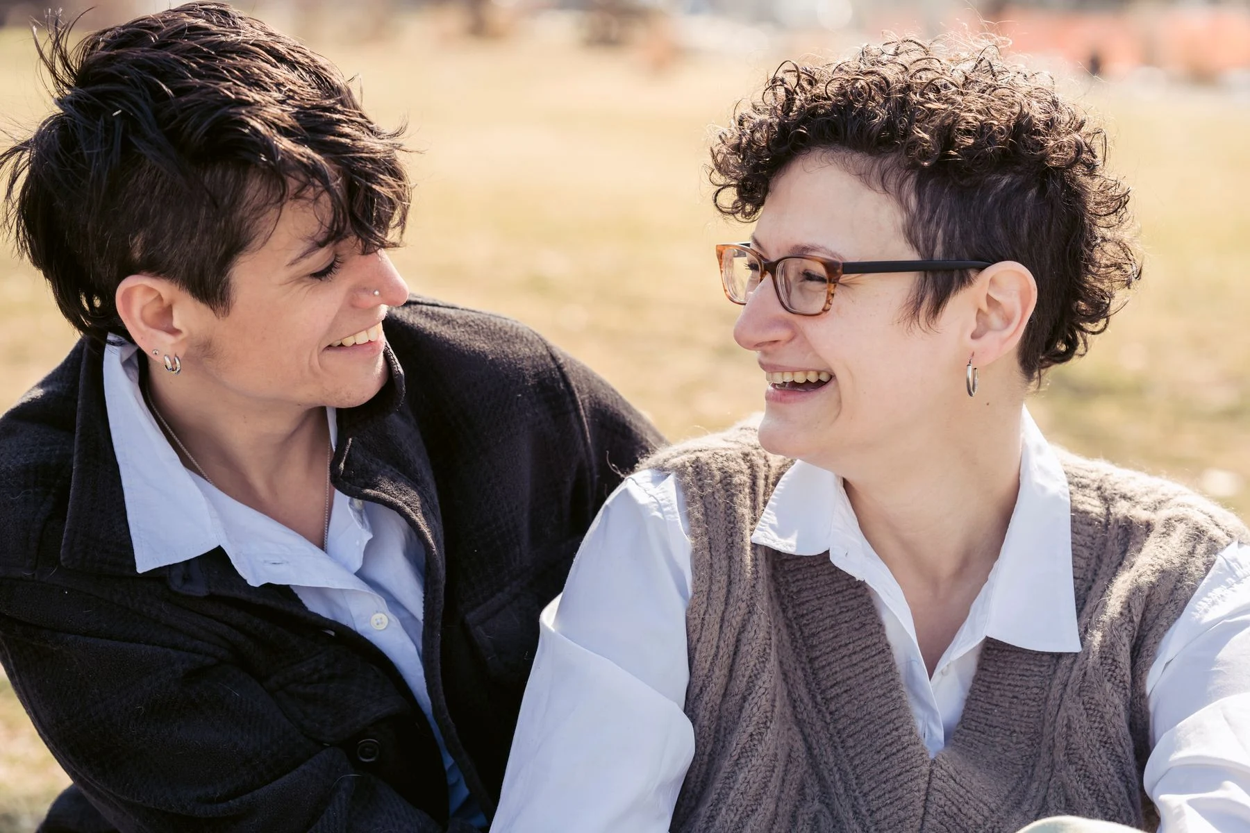 Two people laughing together on a sunny park lawn