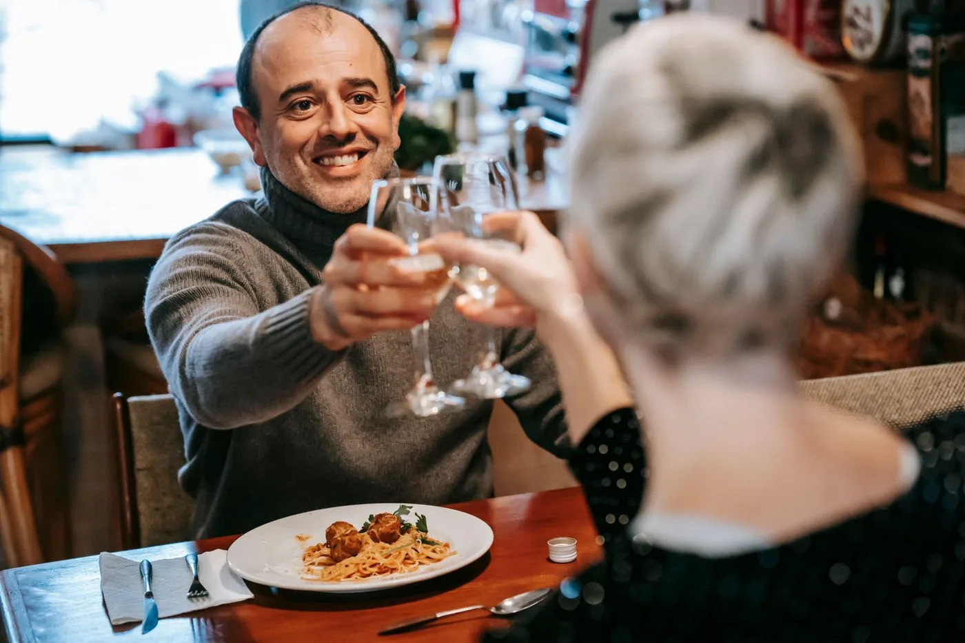 Happy couple toasting with wine at a cozy restaurant dinner.