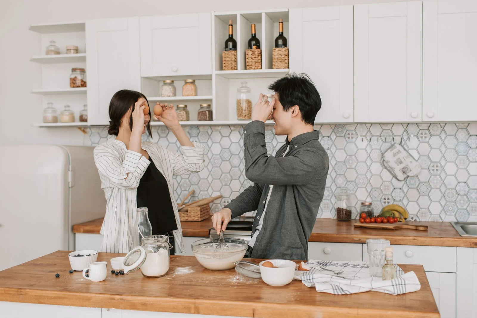 Playful couple baking together in a stylish kitchen, sharing a lighthearted cooking moment.