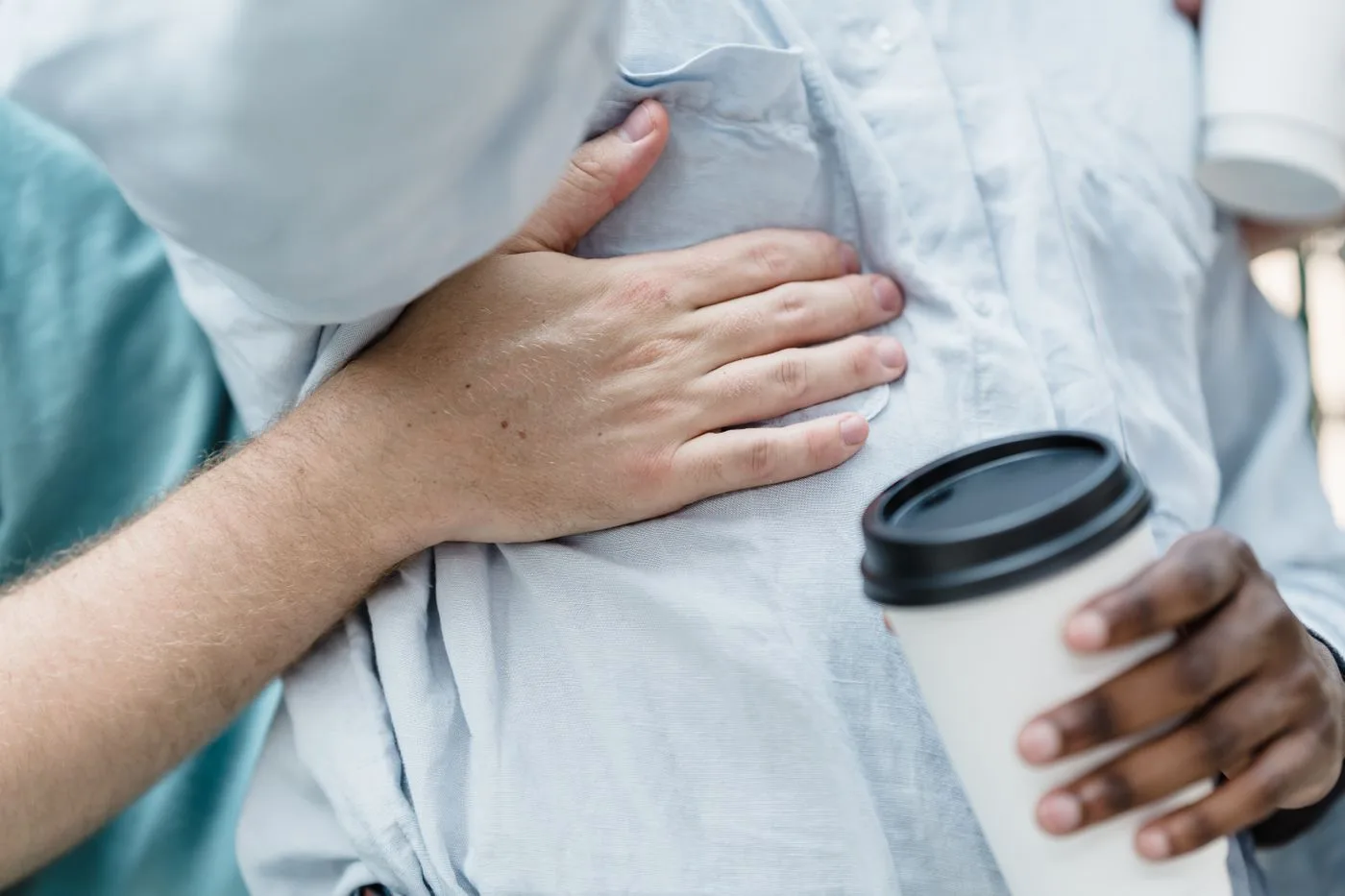 Close-up image of an interracial couple embracing while holding coffee cups, expressing warmth and connection.