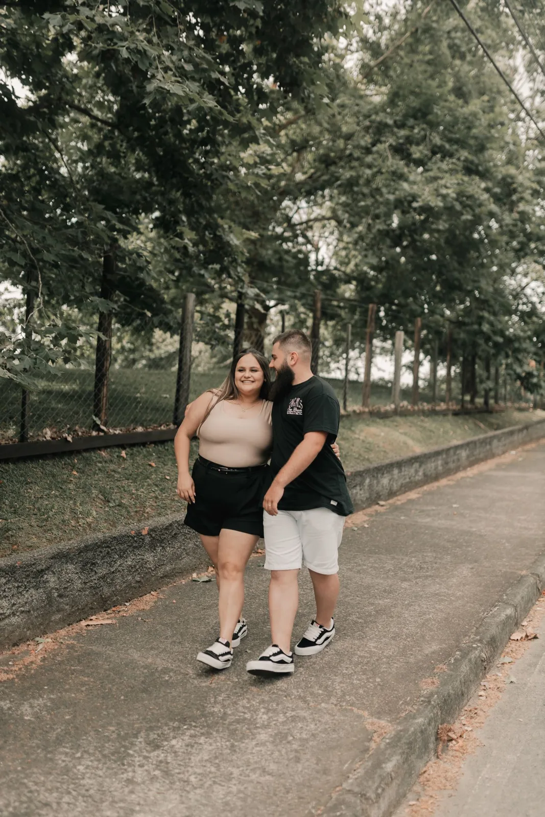 Happy couple strolling along a tree-lined path during the day, enjoying each other's company.