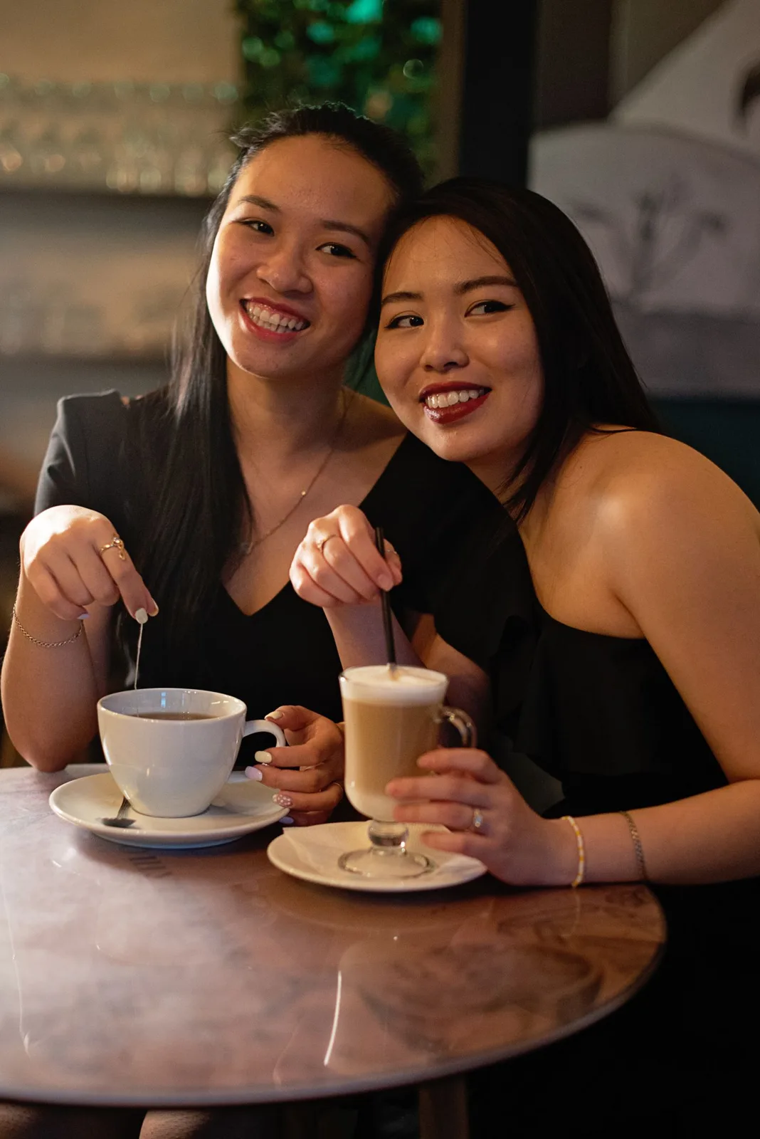 Lesbian couple sharing a warm moment over coffee in a cozy cafe setting.