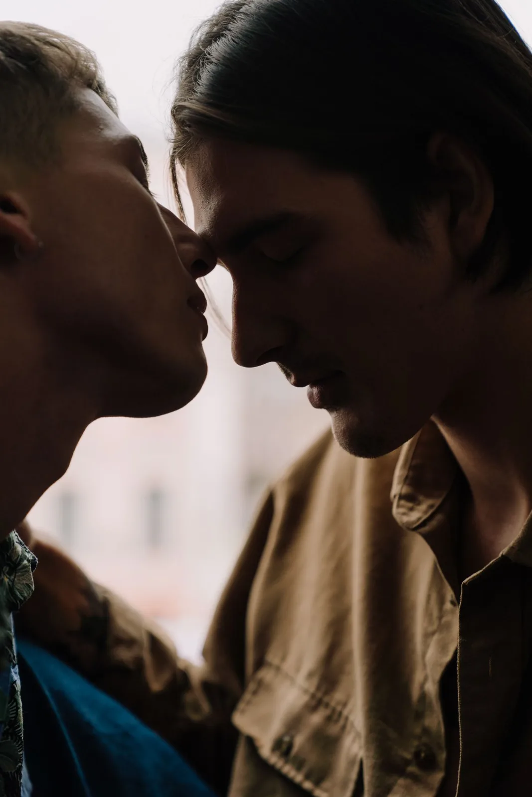 Close-up of two men sharing a tender kiss indoors.