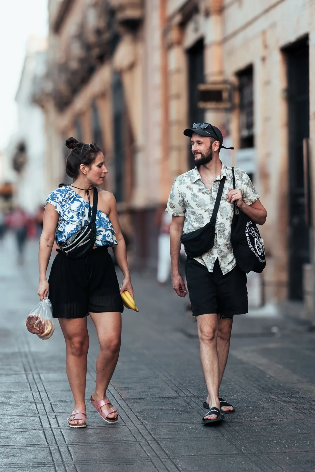 Young couple walking on a summer city street, enjoying a casual day out in urban surroundings.