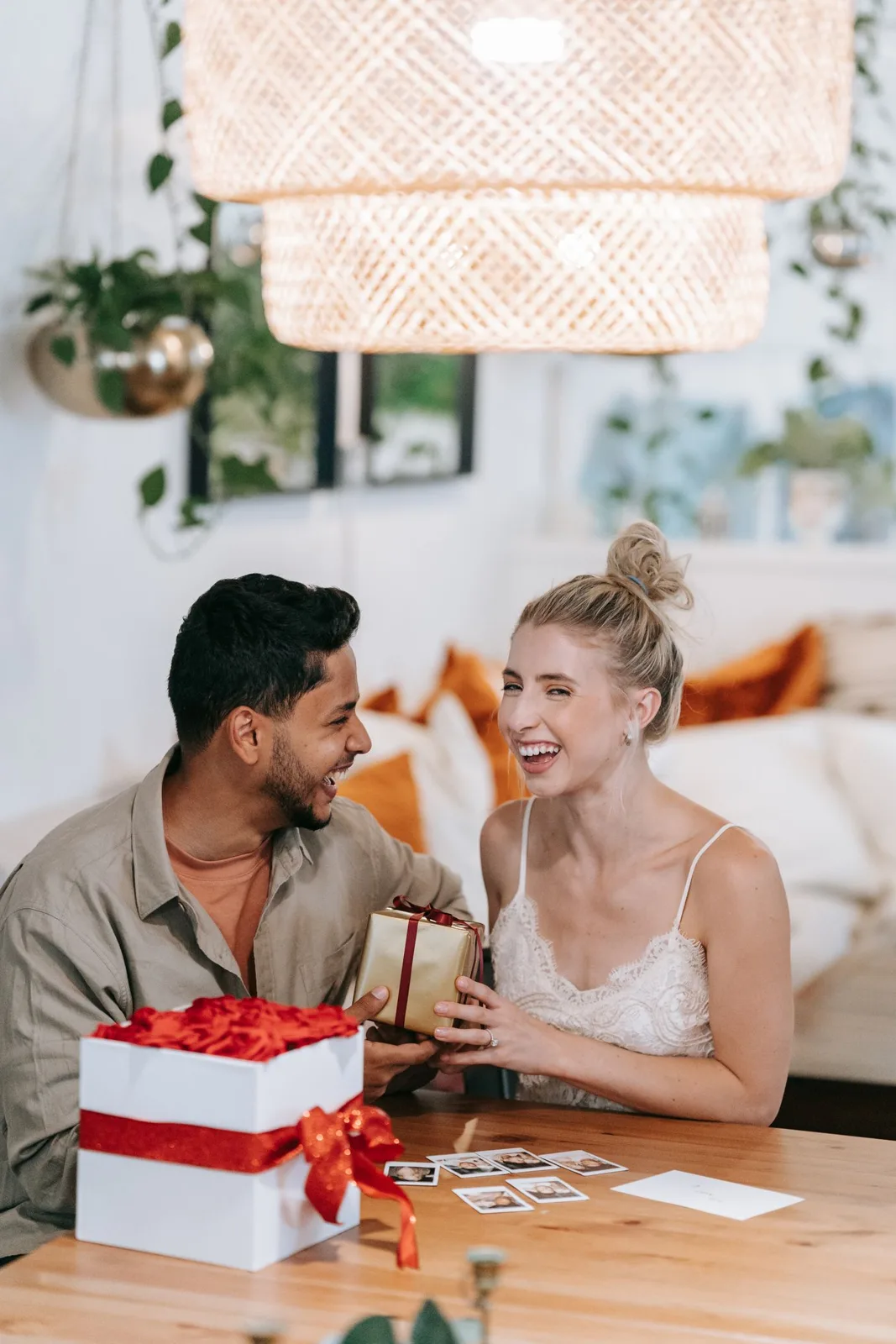 Happy couple laughing and exchanging gifts at a cozy indoor setting.