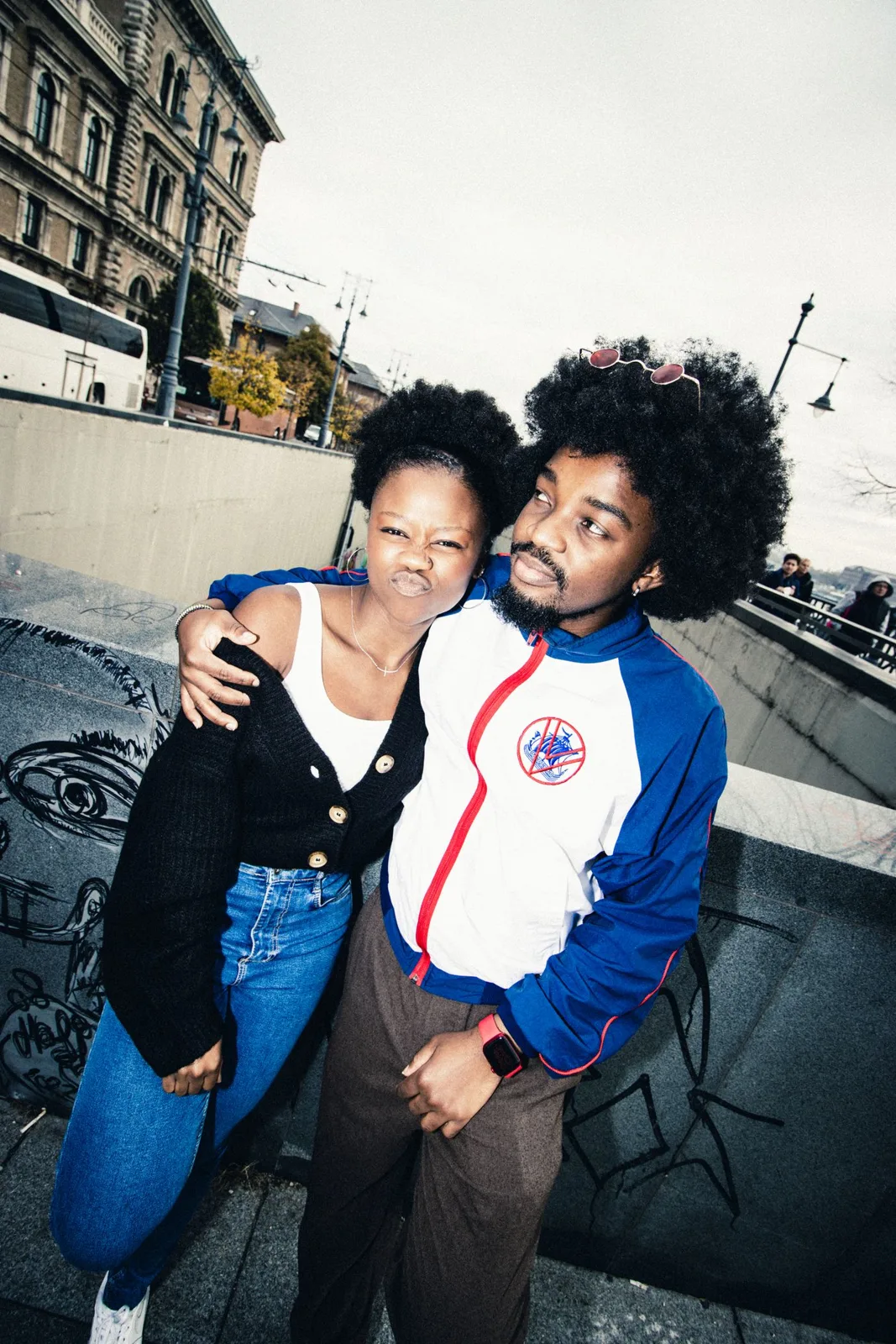 A young couple enjoys a playful moment on a city street in autumn.