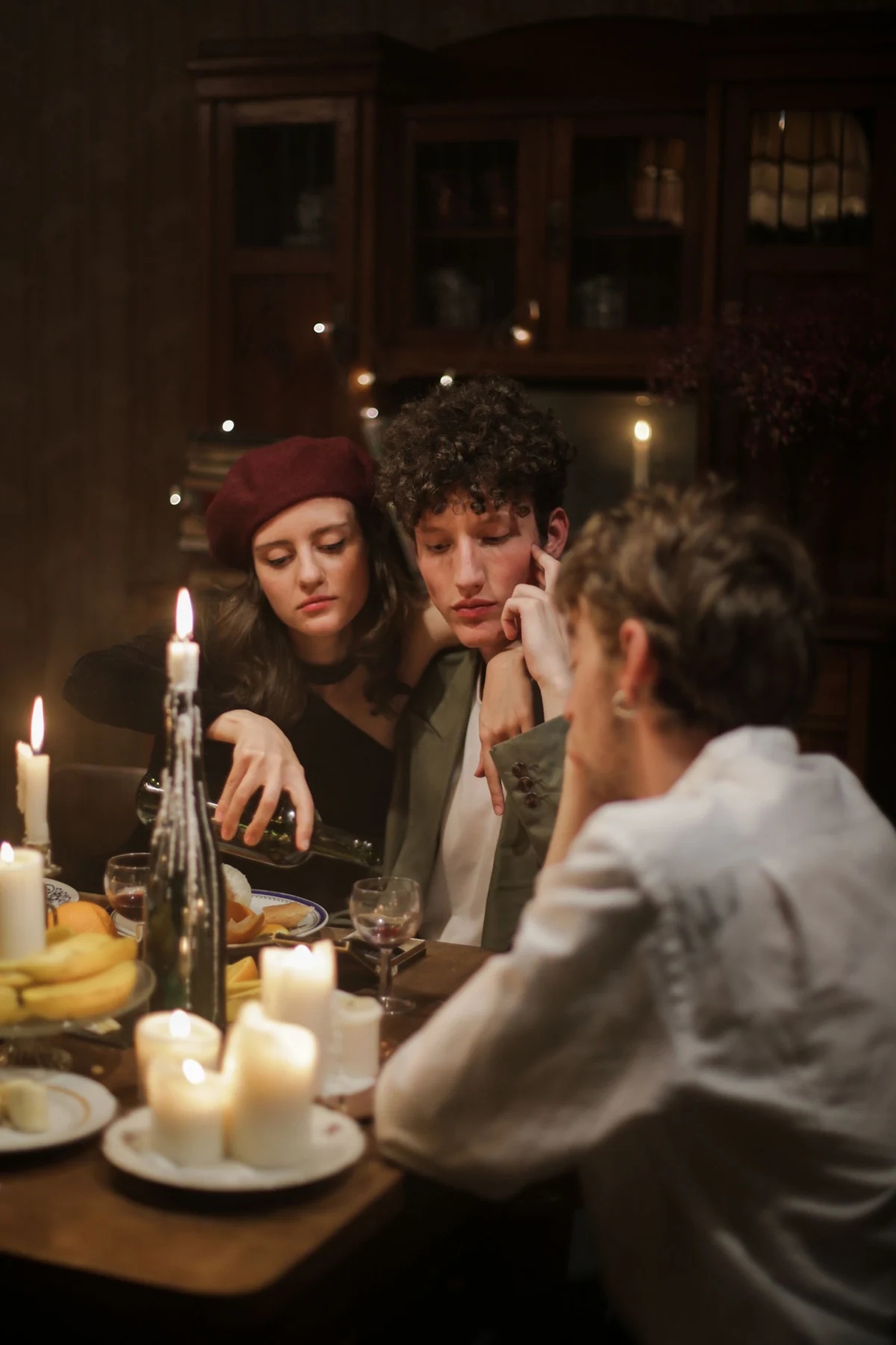 Three adults sharing a candlelit dinner